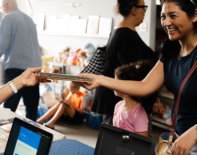 Woman being handed a stack of books at checkout.