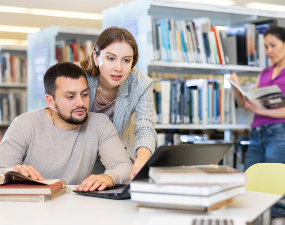 A volunteer helps a patron with digital access on their laptop.