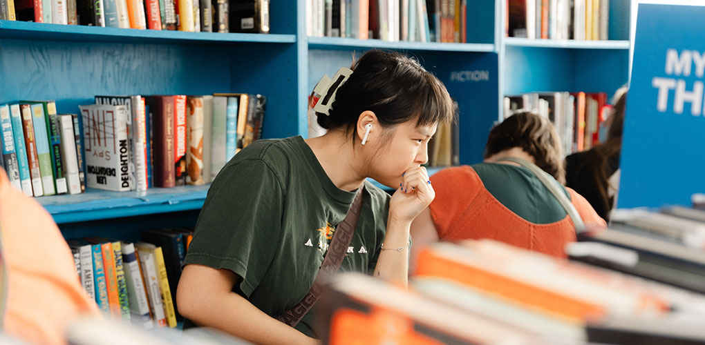 Woman looking through shelves of books.