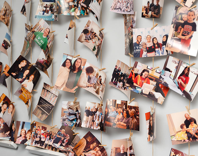 Group of photos of library patrons and volunteers hung on a board.