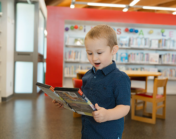 Young boy holding games in the library.