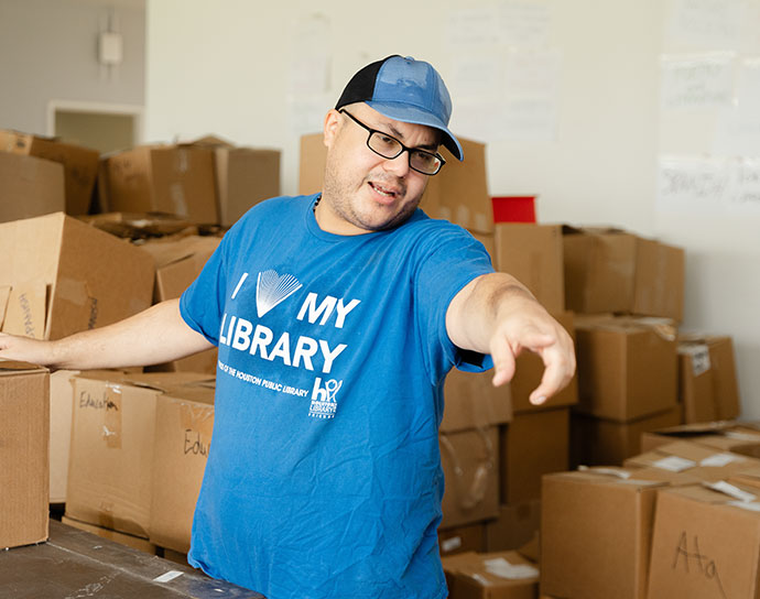 Volunteer directing other volunteers and wearing an "I heart my library" t-shirt.