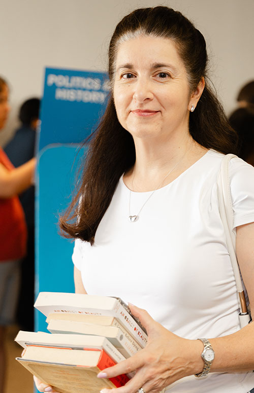 Woman carrying a stack of books at a book drive event.