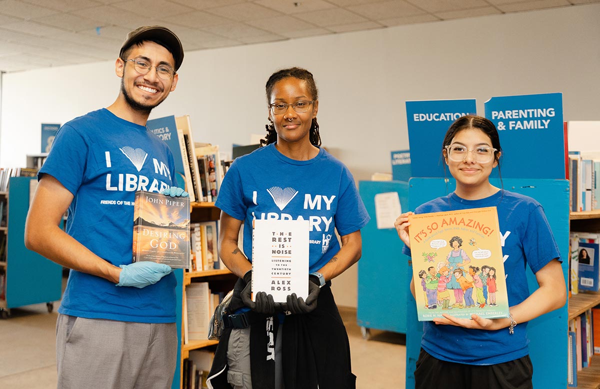 Volunteers for Friends of the Houston Public Library hold up books in the warehouse.